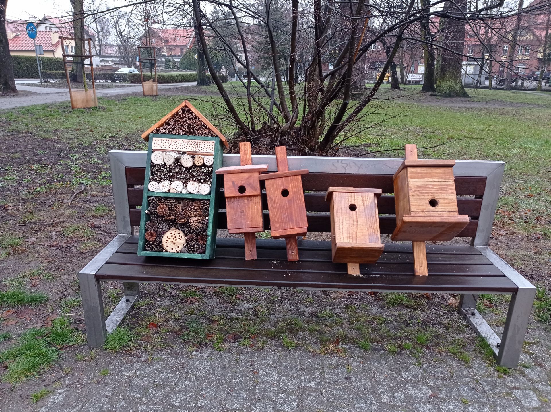 budki lęgowe i domki drewniane dla owadów leżące na ławce