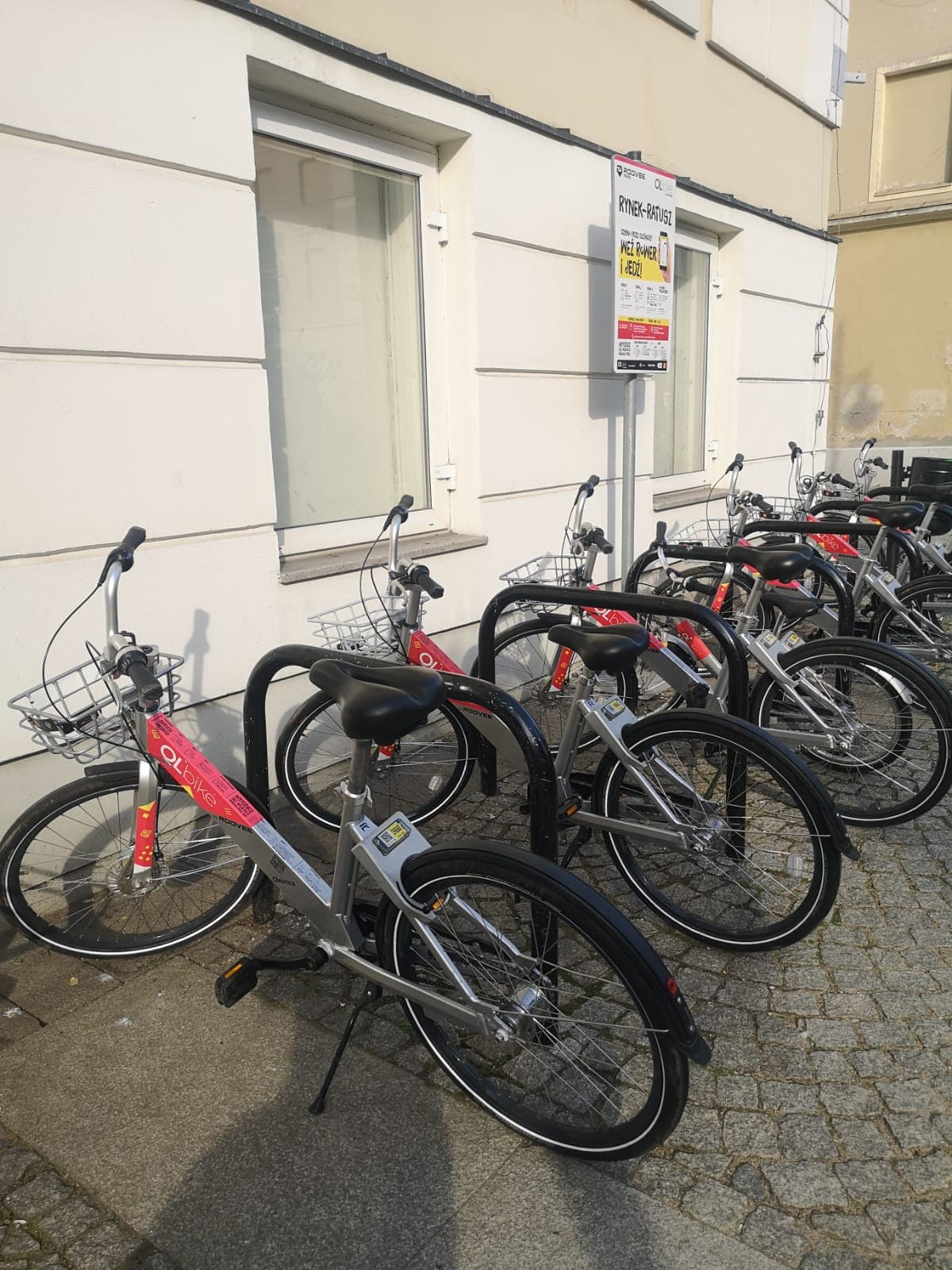 rowery miejskie stojące przy fasadzie budynku
