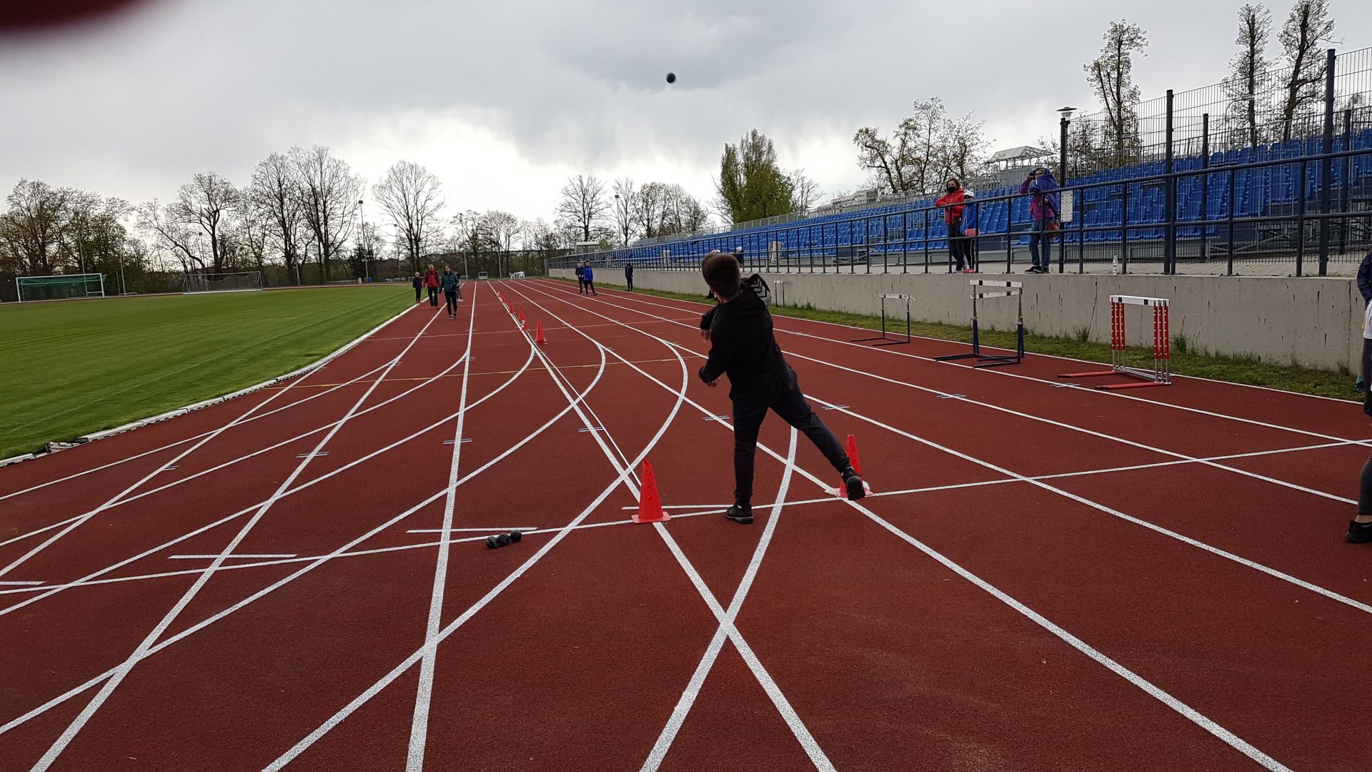 dziewczynka rzucająca piłką w dal na stadionie